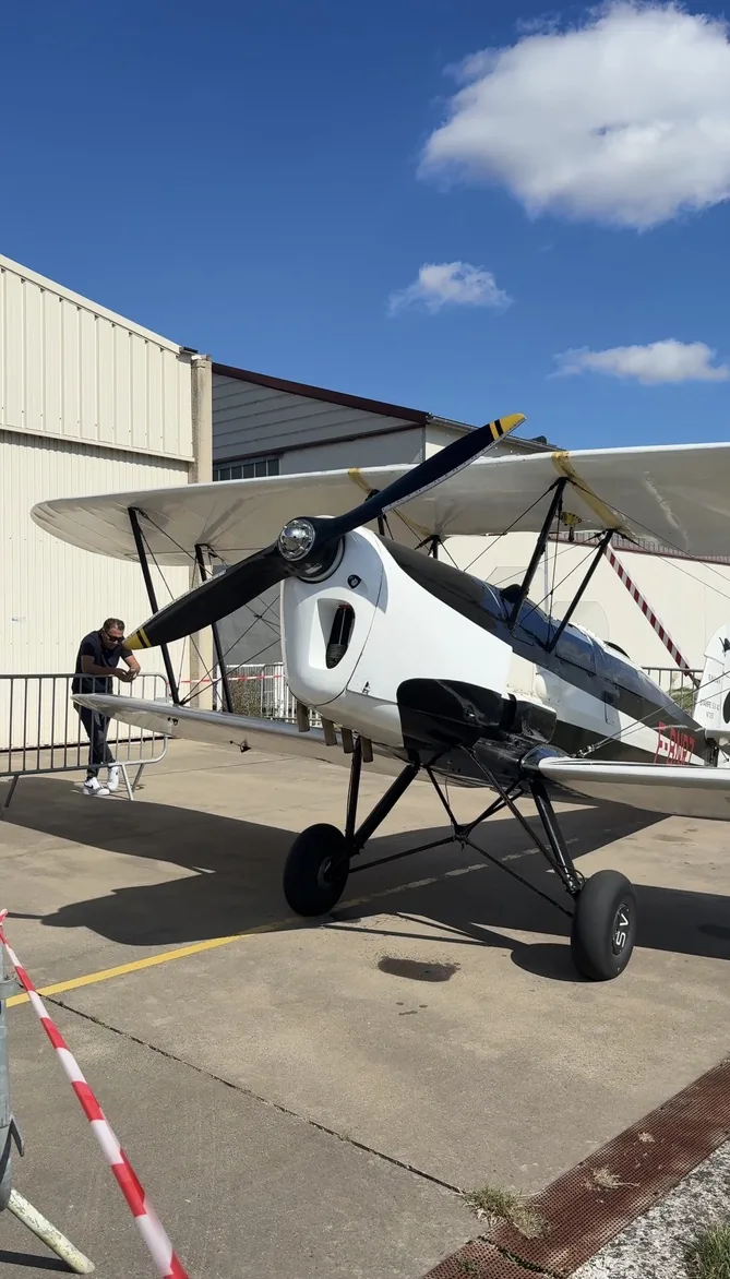 Biplan blanc et noir exposé devant un hangar de l'aérodrome de Persan-Beaumont