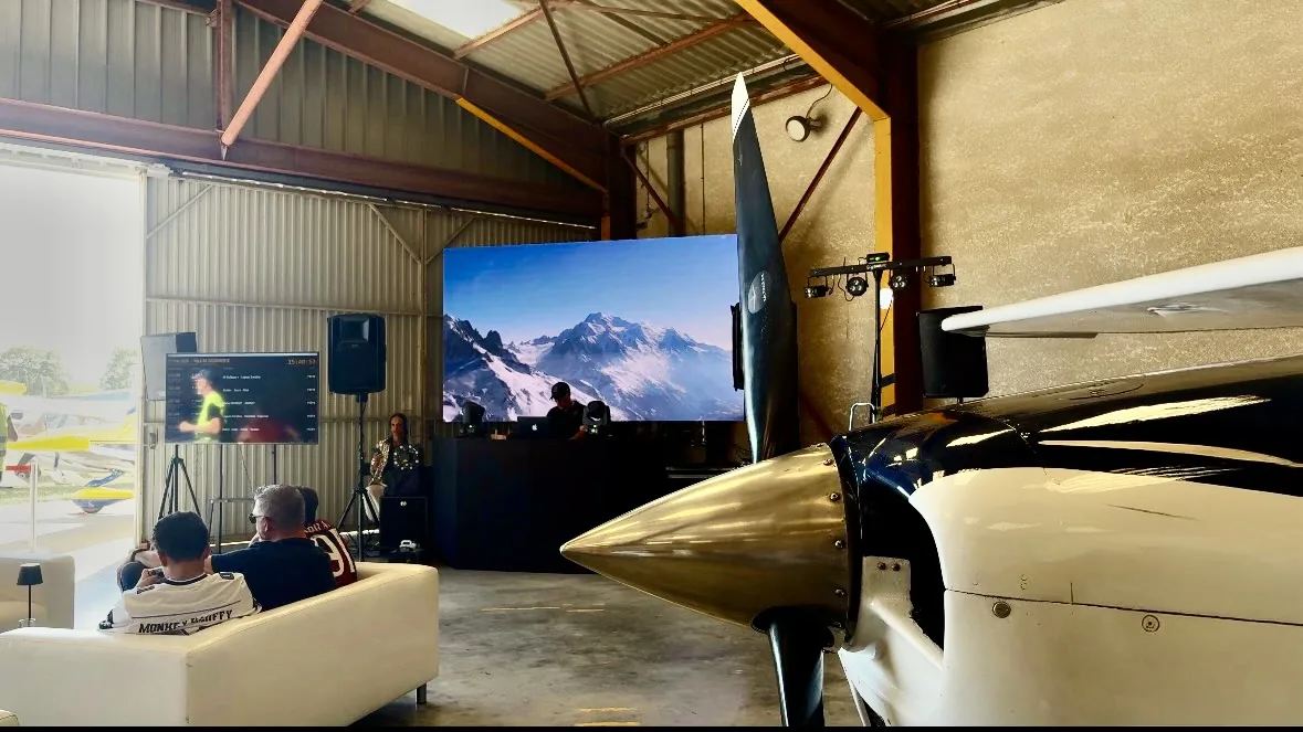Écran géant et sonorisation installés dans le hangar pendant le Fly-in, une hélice au premier plan